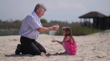 Sahilde dedesi olan kız, kum oynuyorlar. 4k Yavaş Mo