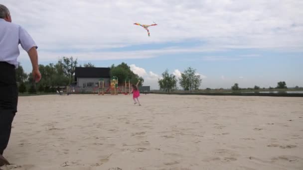 Девушка с дедушкой запускает воздушного змея. Девушка радостно бежит. 4K Slow Mo — стоковое видео