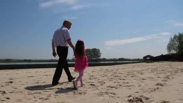 Farfar och barnbarn går på stranden längs sjön. 4K långsam Mo — Stockvideo