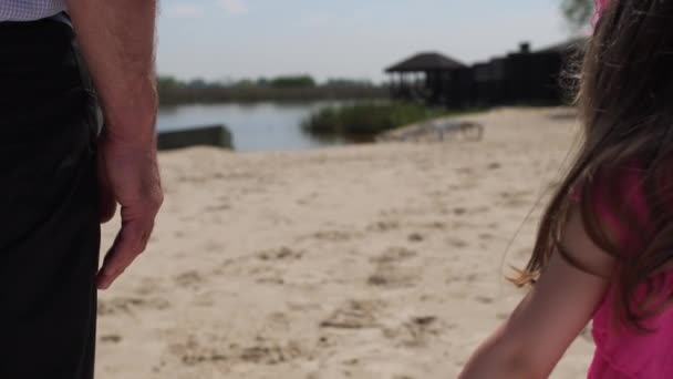 El abuelo toma a una nieta de la mano. Están caminando por la playa. 4K Slow Mo — Vídeo de stock