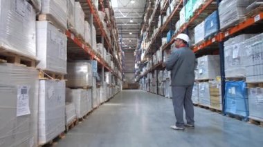 Lojistik deposu. İşçi paketi ile standları arasında gider ve notlar yapar. 4k Yavaş Mo