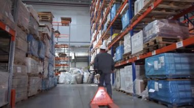 Bir adam lojistik depoda paletler için asansör taşır. 4k Yavaş Mo
