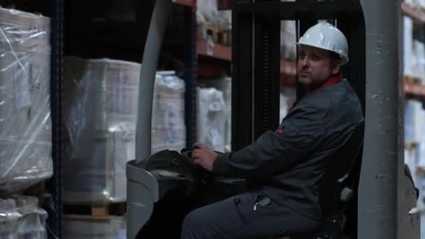 A man in a helmet riding a forklift along the warehouse. 4K Slow Mo — Stock Video