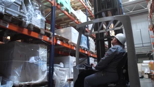 Entrepôt logistique. Un homme se déplace dans une voiture spéciale, soulève les marchandises sur l'étagère. Mo lent 4K — Video