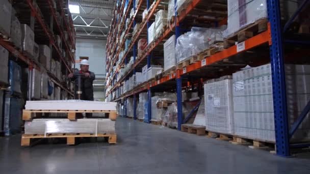 Um trabalhador de armazém carrega caixas enormes em uma empilhadeira manual. 4K Mo lento — Vídeo de Stock