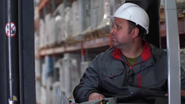 Close-up. Het gezicht van de bestuurder van een vorkheftruck. Een man werkt in een logistiek magazijn. 4k slow mo — Stockvideo