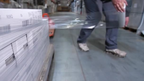 Közeli. Egy férfi csomagolás egy raklap dobozok műanyag csomagolást. 4k lassú Mo — Stock videók