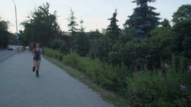 Özel ayakkabılı bir kız, Kangoo Jump, parkta yol boyunca koşar. 4k Yavaş Mo