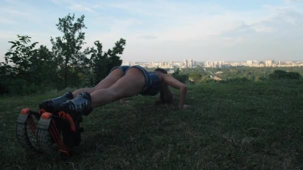 Een meisje op de achtergrond van de stad maakt knijpen op het gras in angoo springt schoenen. 4k slow mo — Stockvideo