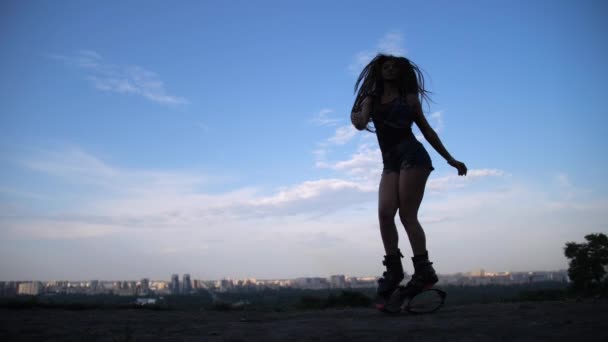 A girl with long hair dancing in angoo jumps shoes in the evening park. 4K Slow Mo — Stock Video