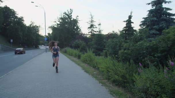 Una chica corre a lo largo de la carretera en zapatos de salto de angoo. 4K Slow Mo — Vídeo de stock