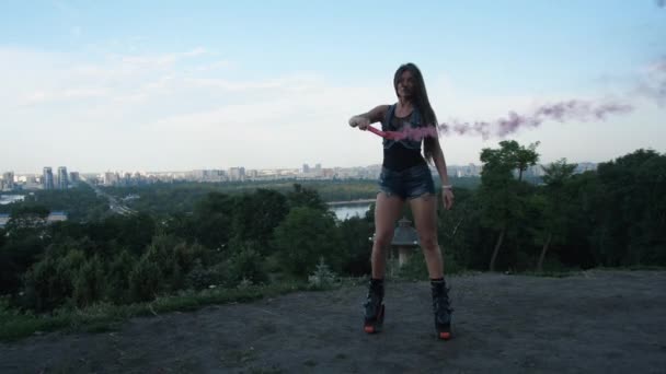 Meisje dansen met roze rook in laarzen angoo springt. In het park van de stad. 4k slow mo — Stockvideo