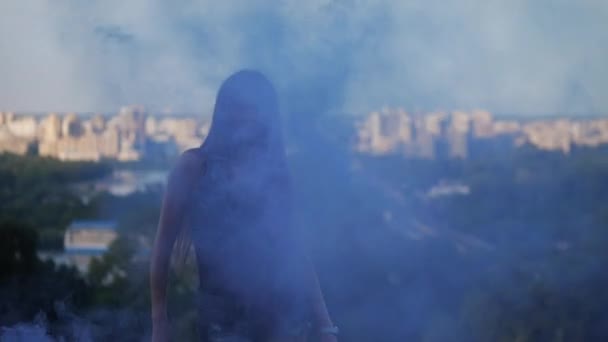Seorang gadis seksi dengan asap biru anggun menari dengan latar belakang asap. 4K Mo Pelan — Stok Video