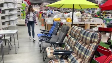 Büyük bir süpermarkette genç kadın bir şezlong seçer. 4k Yavaş Mo