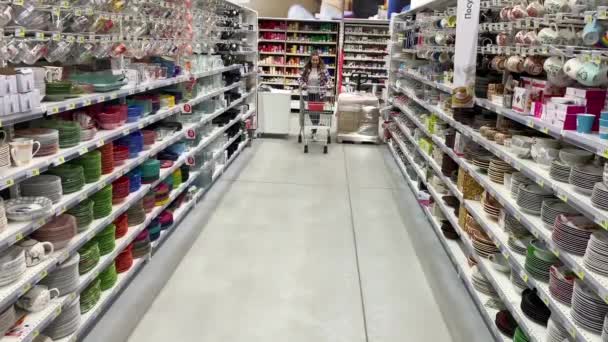 Jonge vrouw heeft plezier rijden een trolley in een supermarkt. 4k slow mo — Stockvideo
