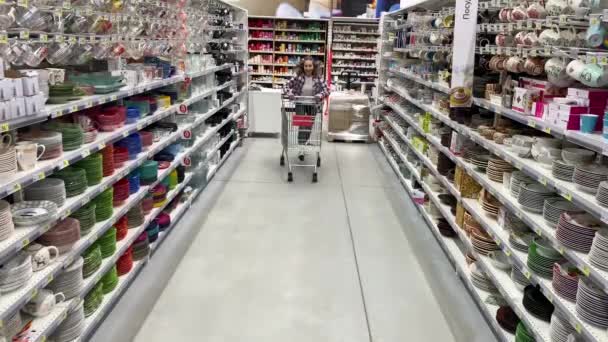 Jovem mulher positiva se divertir no supermercado. A rapariga monta um carrinho. 4K Mo lento — Vídeo de Stock