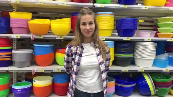 Une jeune femme positive qui s'amuse dans l'hypermarché. La fille a mis sur ses mains des gants multicolores et couvre leur appareil photo. Mo lent 4K — Video