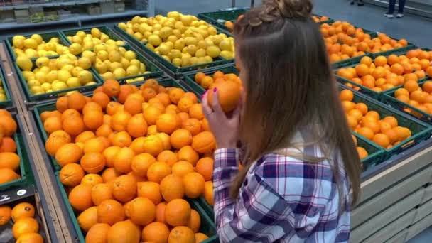 Supermercado. A rapariga do departamento de fruta apanha laranjas. 4K Mo lento — Vídeo de Stock