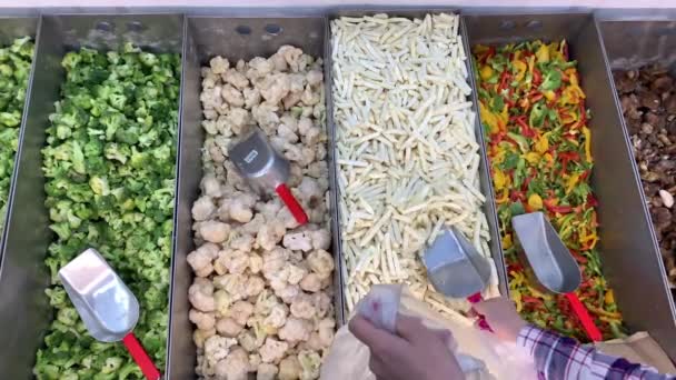 Szupermarket. Egy nő felvette a fagyasztott burgonyát egy zsákba. A hűtőszekrényben fagyasztott zöldségek. 4k lassú Mo — Stock videók