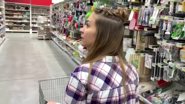 スーパー マーケット。女性は家庭用品を持って棚の間を歩く。4k スローモー — ストック動画