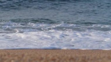 Okyanus kıyısı. Kumlu plaj, deniz köpüğü ile mavi dalgalar. 4k Yavaş Mo