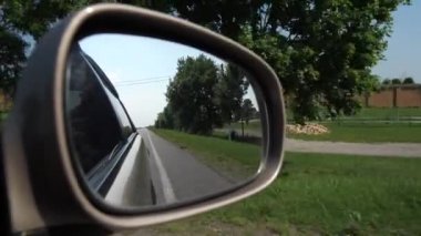 Arabanın yan aynasına ateş ediyor. Araba kırsal kesimde hareket ediyor. 4k Yavaş Mo