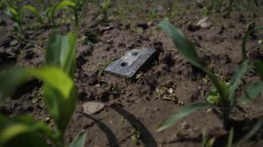 Eski kaset kaseti yerde kırıldı. Genç bitkiler yeni dijital çağın bir sembolü olarak etrafta filizleniyor. 4k Yavaş Mo