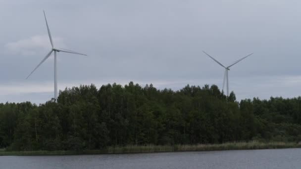 Огромные ветряные мельницы стоят в лесу у озера. Новые технологии. 4K Slow Mo — стоковое видео