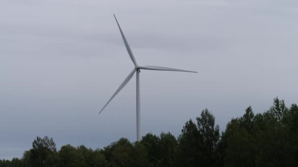 Die Windmühle erhebt sich über dem Wald und erzeugt Energie. 4k langsam mo — Stockvideo