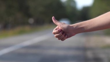 Kadın parmağının baş parmağının yakın çekimi. Kız yolda arabayı durdurmayı deniyordu. 4k Ağır çekim