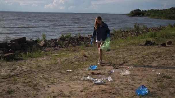 若い女性が海岸でプラスチックごみを収集します。4kスローモーメント — ストック動画