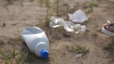 Yakın plan. Plastik bir şişe yere yatar, eldivenli bir kadın el onu alır ve bir torbaya atar. 4k Ağır çekim