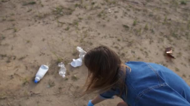 Una giovane donna raccoglie rifiuti di plastica sulla natura. La ragazza mette la spazzatura in una borsa. 4K Lento Lu — Video Stock