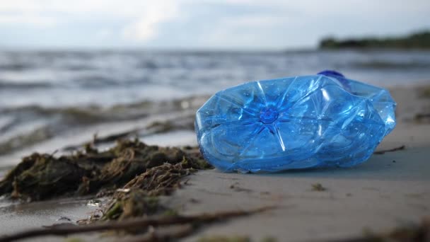 Close-up. Perto do mar encontra-se uma garrafa de plástico. Poluição ambiental por plástico. 4K Mo lento — Vídeo de Stock