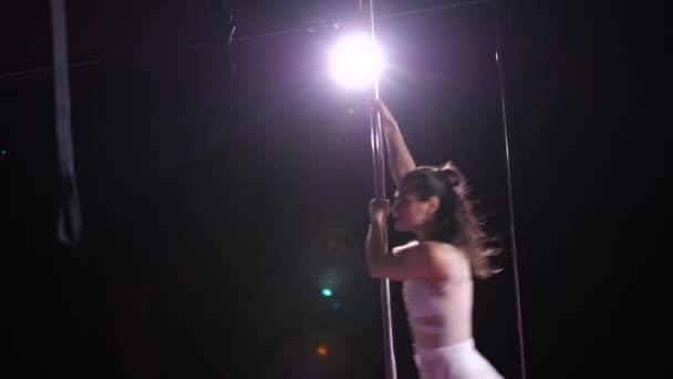 Танцовщица в полупрозрачном белом платье делает сексуальные движения на пилоне. 4K Slow Mo — стоковое видео