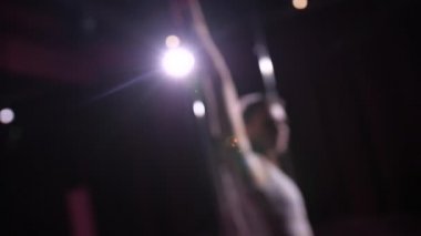 Defocus direğin yanında dans ediyor. Karanlık bir stüdyo, kamerada bir spot ışığı parlıyor, beyazlı bir dansçı direğin yanında dönüyor. 4k Ağır çekim