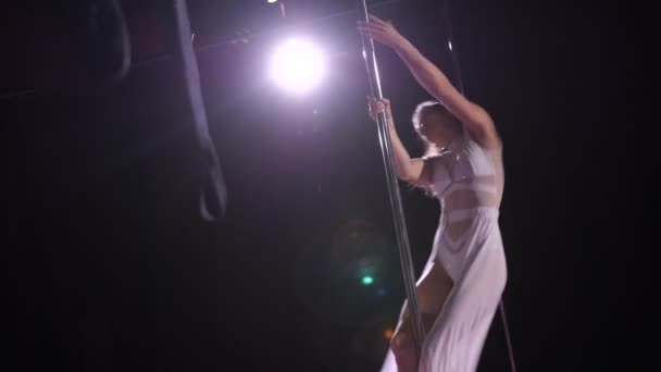 Danser gracieusement sur le pylône. Une fille en robe blanche joue des tours de danse. Mo lent 4K — Video