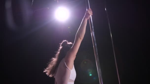 Dancing on a pylon in a dark studio. Professional dancer is spinning in a translucent dress. 4K Slow Mo — Stock Video