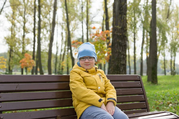 Chłopiec Żółtą Kurtkę Odpoczywa Jesienny Park — Zdjęcie stockowe