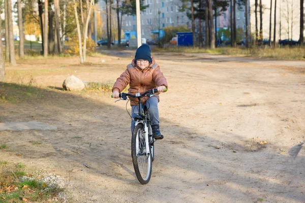 男孩用眼镜和温暖的衣裳骑自行车 — 图库照片
