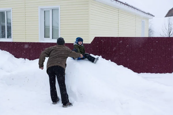 祖父母の世話に雪に覆われた丘の上に乗る小さな男の子 — ストック写真