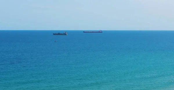 Blue sea surface with small ships on the horizon — Stock Photo, Image