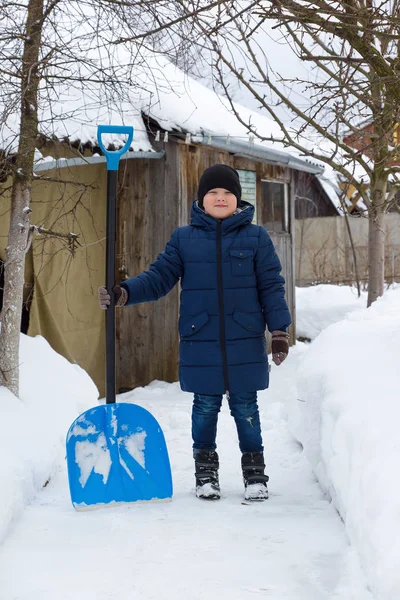 Boy clears snow with a shovel in winter — Stock Photo, Image