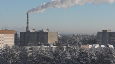 Yüksek fabrika bacası şehrin üzerine duman üfler