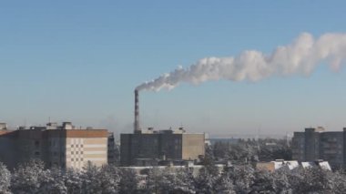 Yüksek fabrika bacası şehrin üzerine duman üfler