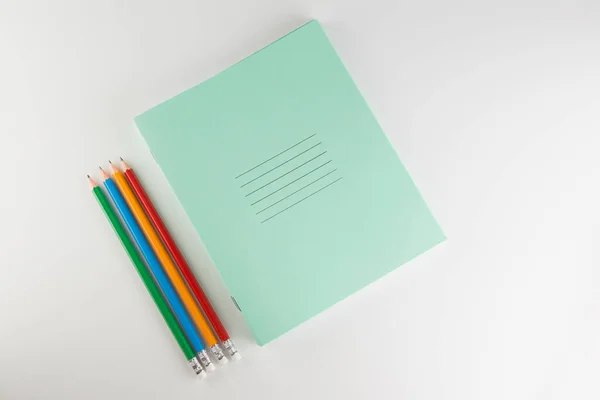 薄い生徒用ノートの山に学校用の色鉛筆 — ストック写真