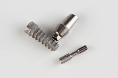 Beyaz zemin üzerinde kilit elementleri izole edilmiş diş titanyum implantı