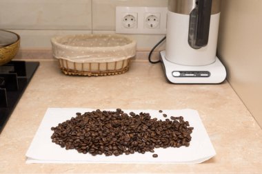 Taze kavrulmuş kahve çekirdekleri masada ve tavada.