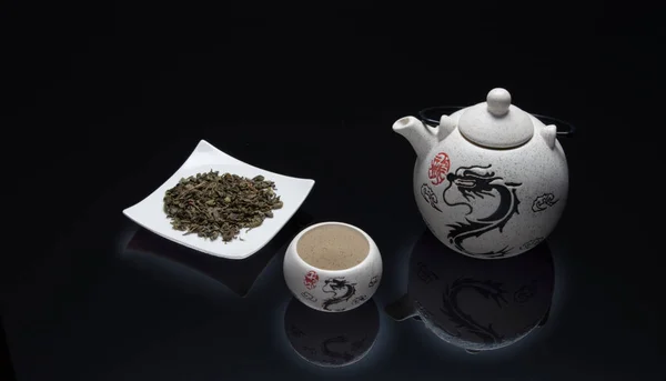 white teapot with drawing of dragon and green tea