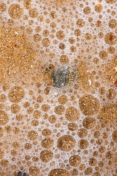 물튀기는 파도에 만들어 해변에 기포들의 — 스톡 사진
